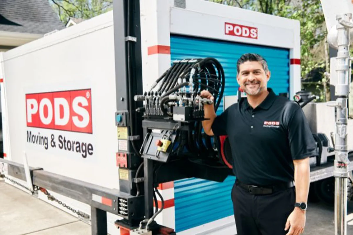 A truck driver stands beside a portable storage container.