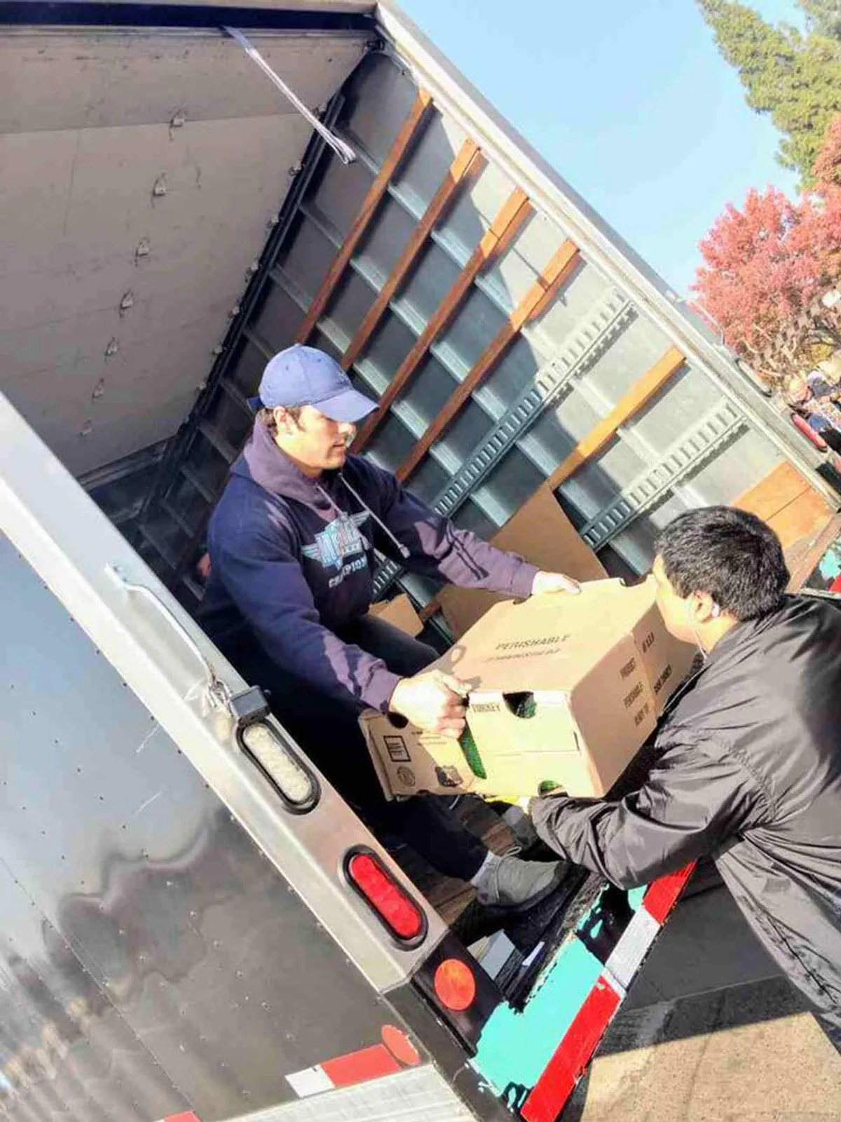 A Meathead Mover handing a box of food to a volunteer.