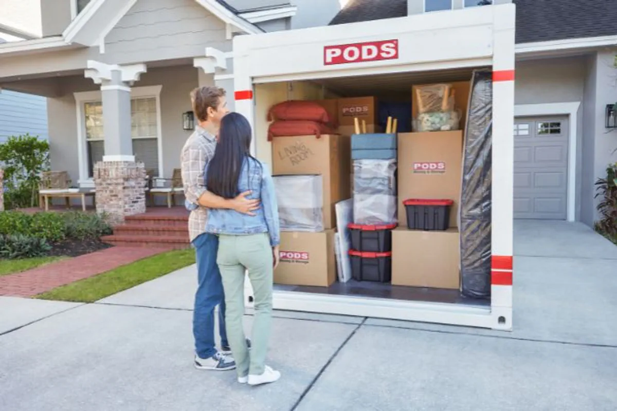 A couple stands beside their loaded portable storage container.