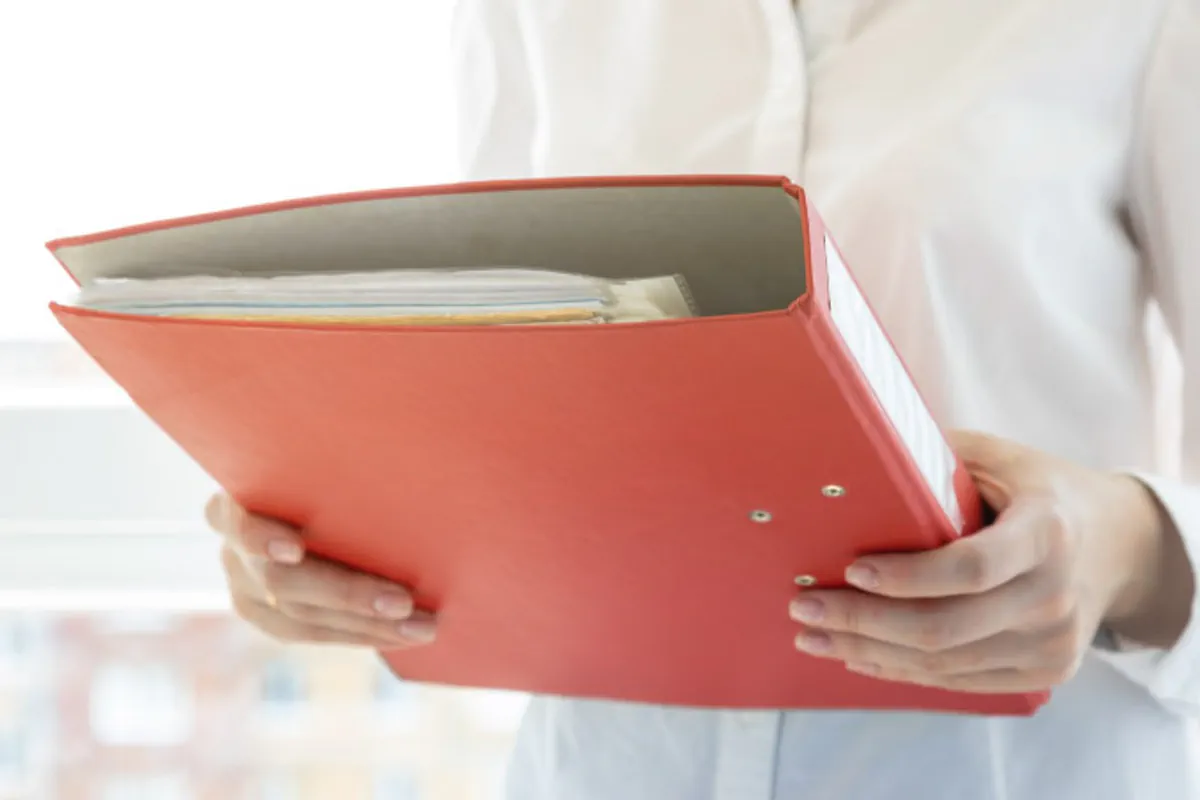 A woman organizes moving documents in a red binder.