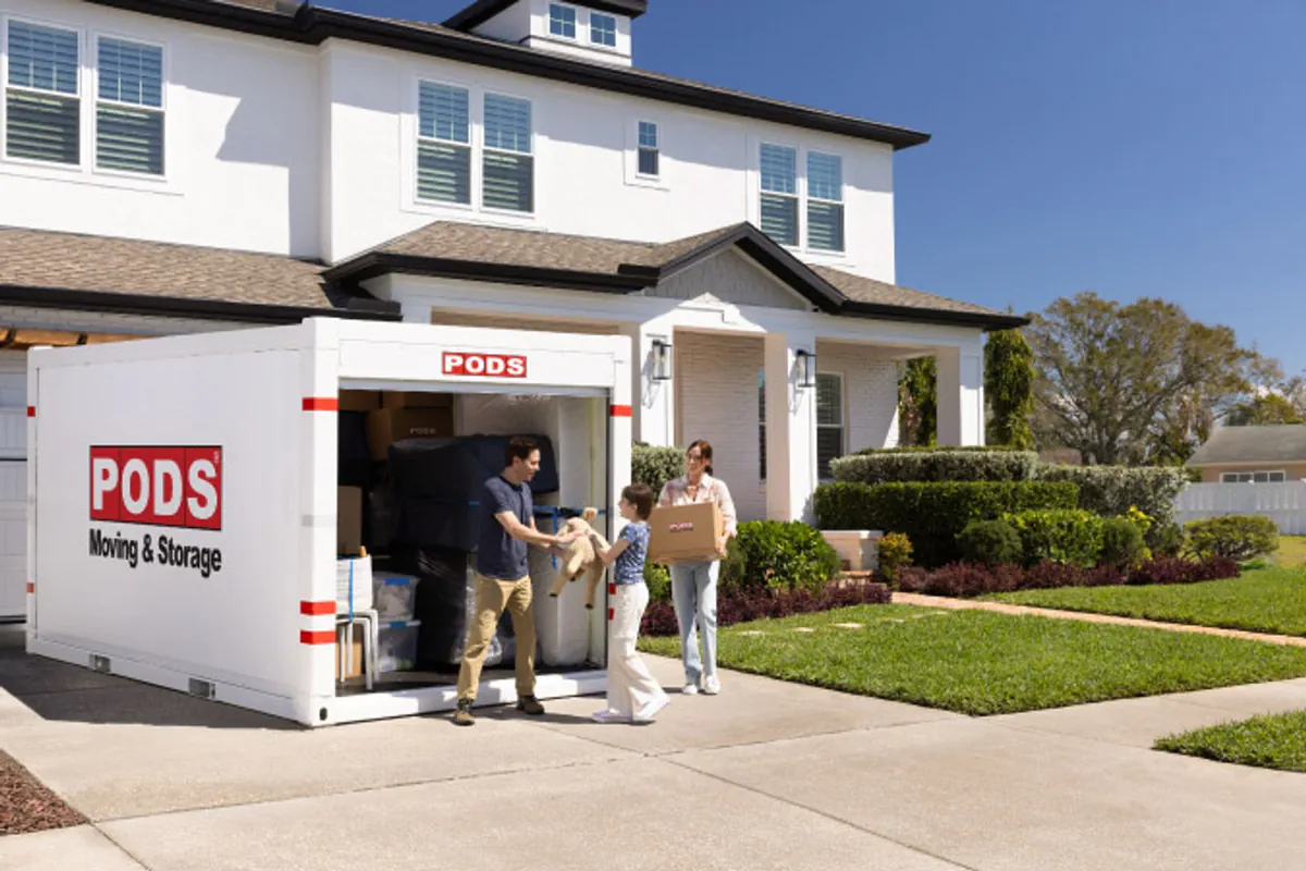 A family loads a portable storage container in a driveway.