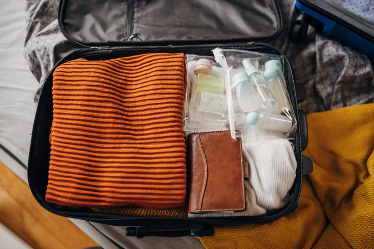 An open suitcase holds clothes and toiletries for a moving-day essentials bag.