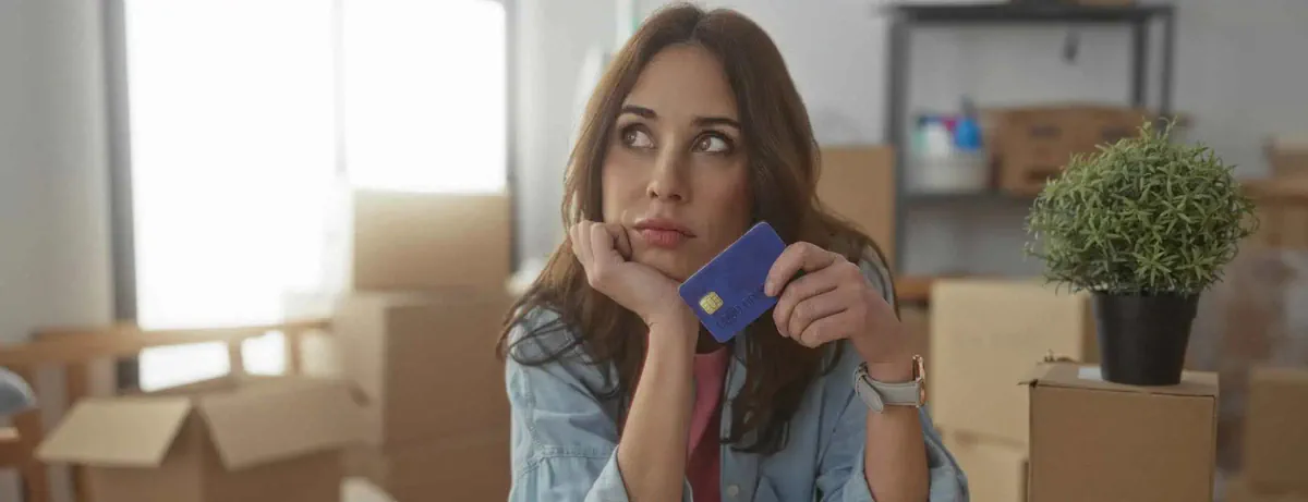 A woman comparing moving costs while seated among moving boxes.